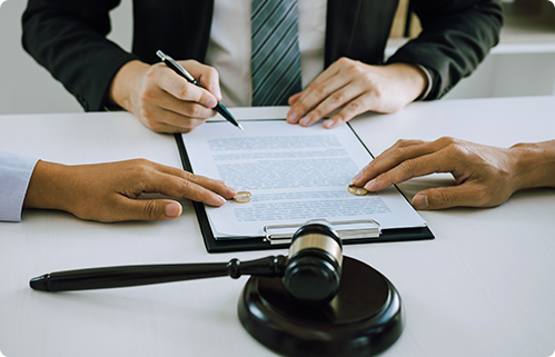  Hands sign legal contract on a desk with a gavel and pen.